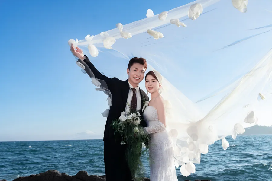 新人站在海岸礁石与长纱之间