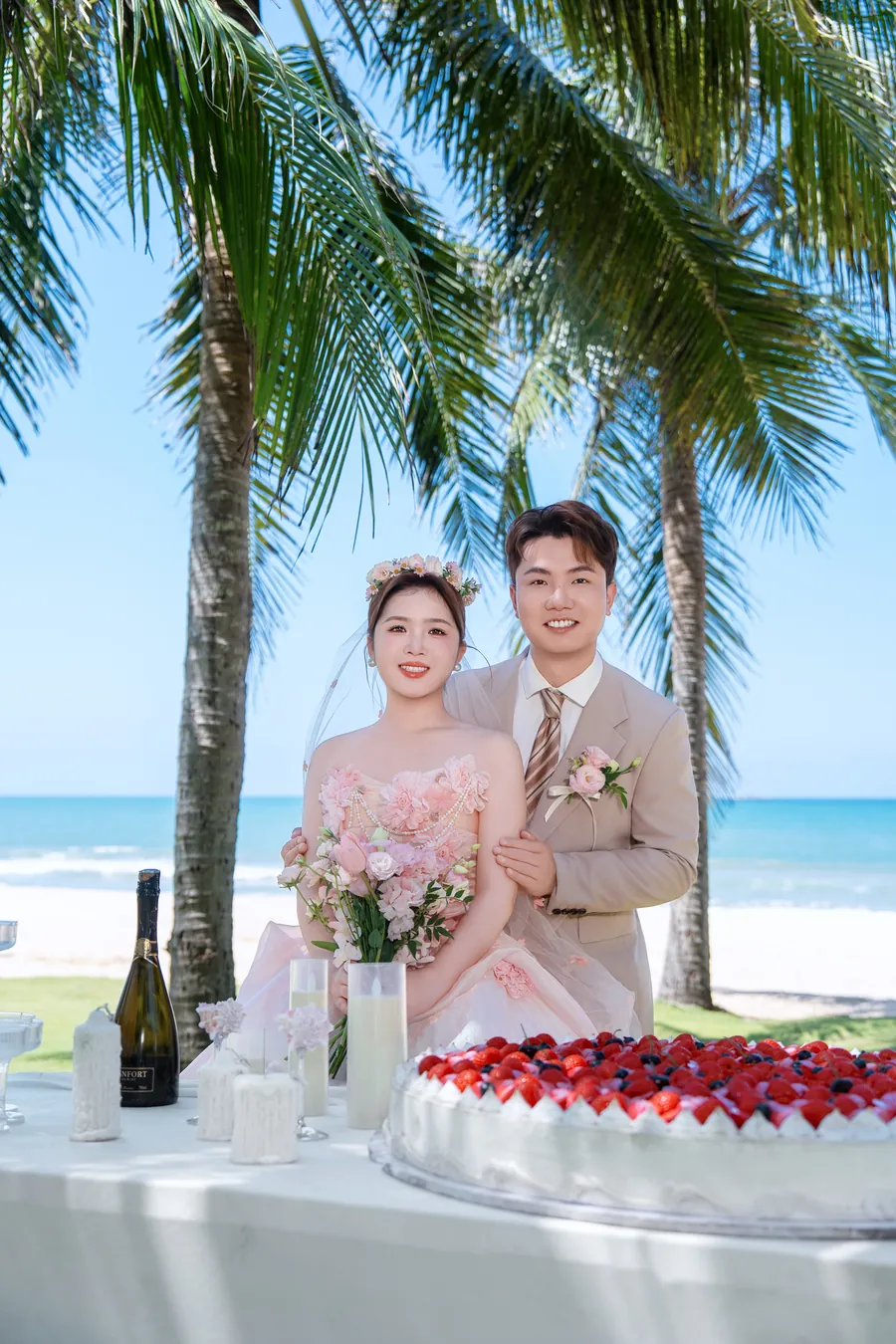 新人在椰林婚礼蛋糕前并肩而立